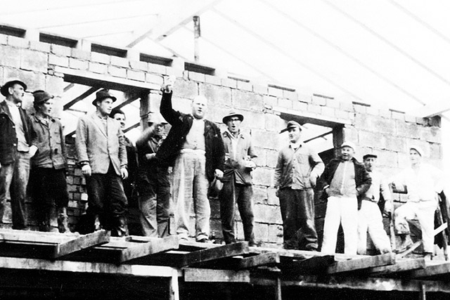 Firmengründer Gregor Müller Senior (mit erhobenem Arm) in seiner aktiven Zimmererzeit bei einem Richtfest zur Fertigstellung des Dachstuhles