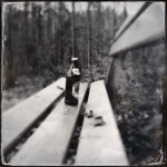 Sitzt eine Bierflasche im Wald auf einer Bank